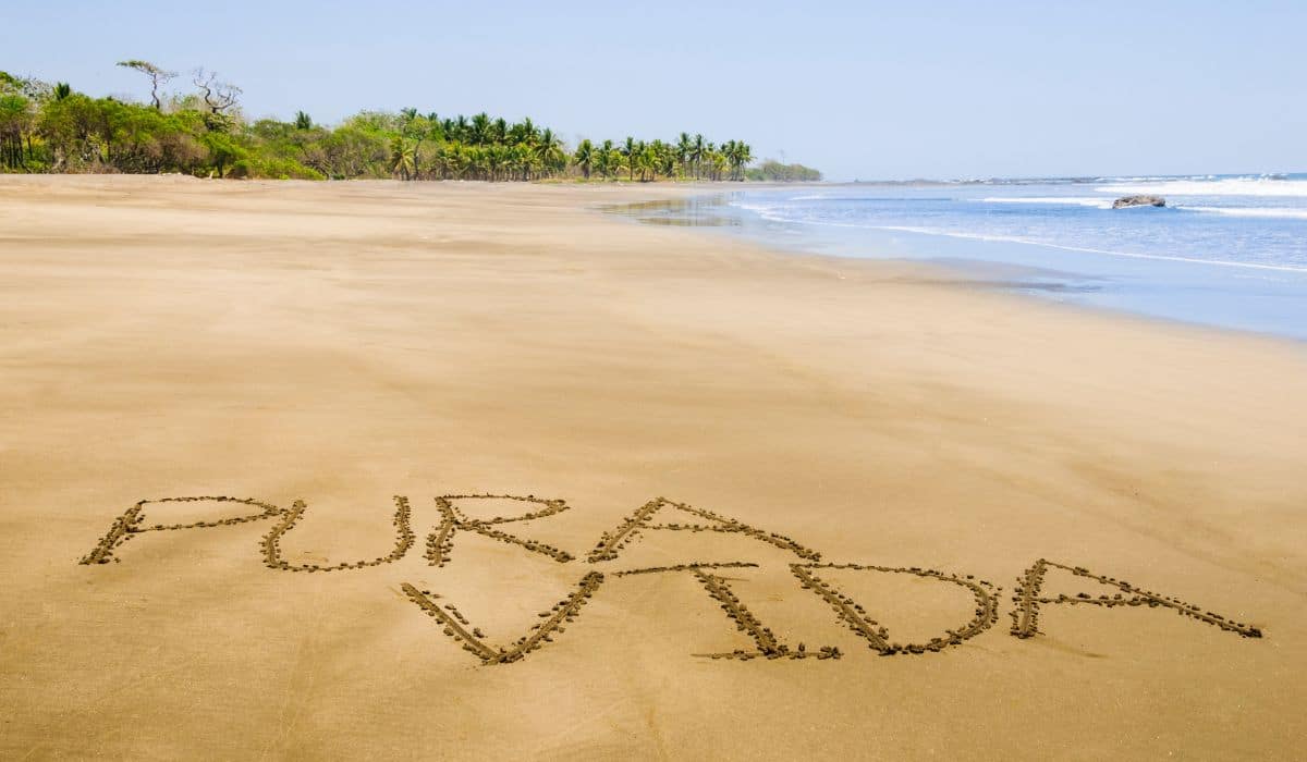 A Costa Rica beach view with the words "Pura Vida" in the sand